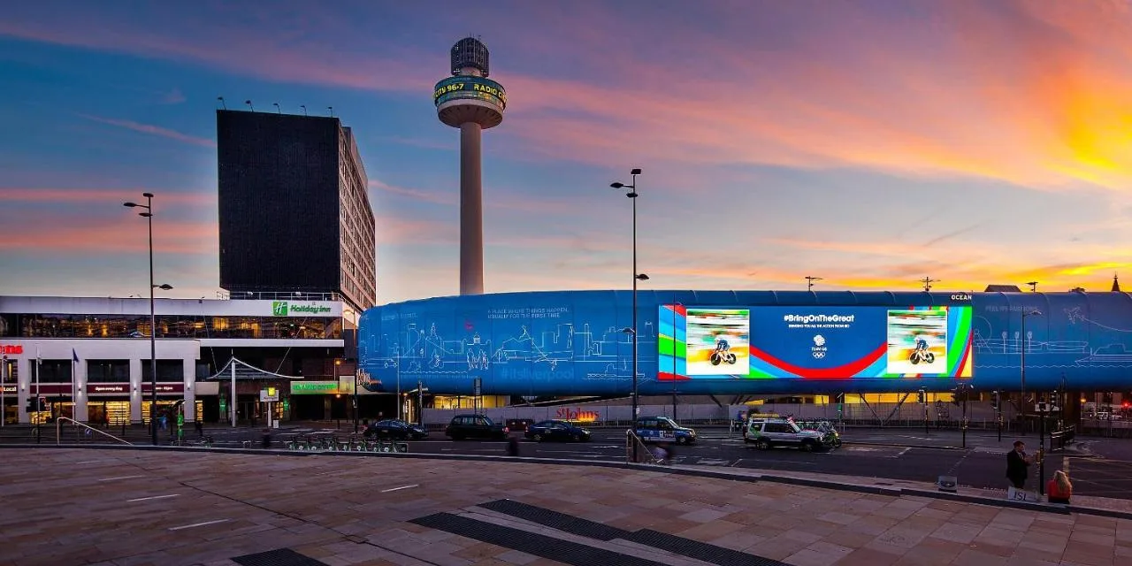 A large blue building in a city with a tower at Holiday Inn Liverpool City Centre by IHG in Liverpool