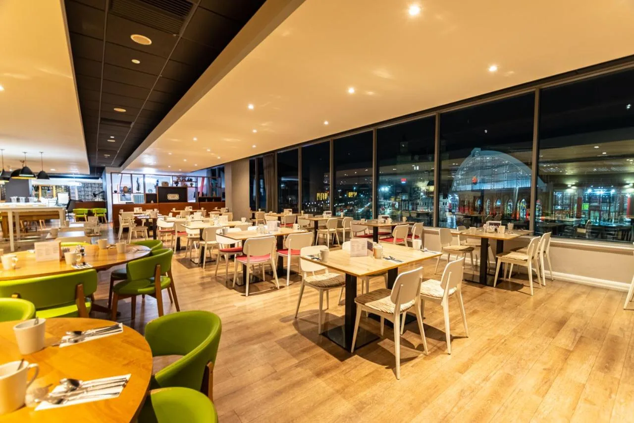 A restaurant with tables and chairs and windows at Holiday Inn Liverpool City Centre by IHG in Liverpool